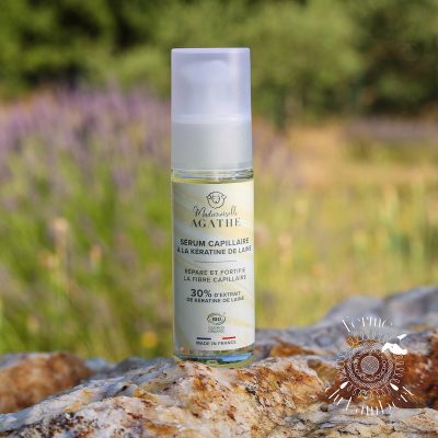 Sérum capillaire à la kératine de laine, posé sur une pierre devant un champ de lavande en Provence