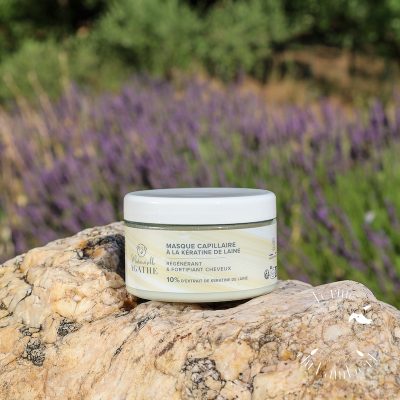 Masque capillaire à la kératine de laine posé sur une pierre blanche avec champs de lavande et maquis provençal