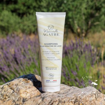 Shampoing à la kératine de laine sur une pierre blanche devant un champ de lavande en Provence