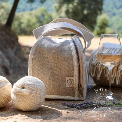Lunch bag isotherme posé sur des marches de pierre avec des pelotes de laine et un verre de rosé